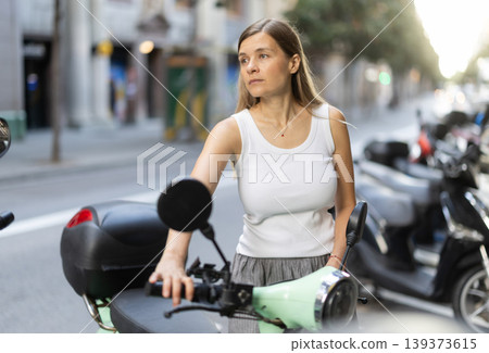 Woman rents moped, starts journey at parking lot Woman rents moped, starts journey at parking lot 139373615