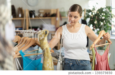 Adult woman choosing summer clothes in store Adult woman choosing summer clothes in store 139373650