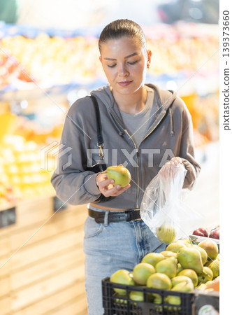 Young woman buyer choosing pears at vegetable market 139373660