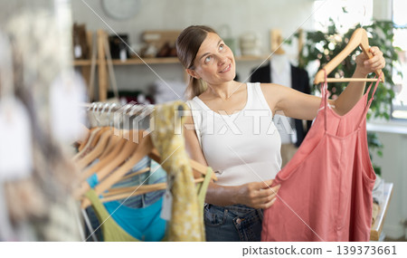 Adult woman choosing jumpsuit in clothing store Adult woman choosing jumpsuit in clothing store 139373661