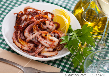 Delicious cooked squid or octopus tentacles with lemon and parsley on a plate Delicious cooked squid or octopus tentacles with lemon and parsley on a plate 139373700