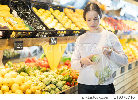 Young woman choosing artichoke in vegetable shop Young woman choosing artichoke in vegetable shop 139373710