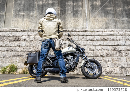 A white cruiser bike and a male rider seen from behind. A white cruiser bike and a male rider seen from behind. 139373728