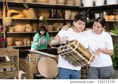 guy and girl choose folding wooden furniture for country house in store guy and girl choose folding wooden furniture for country house in store 139373795