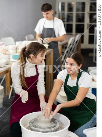 Woman working with pottery wheel and master giving instructions 139373810