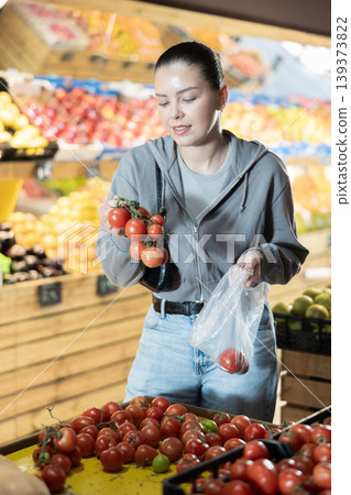 Young woman buyer choosing tomatoes at vegetable market 139373822