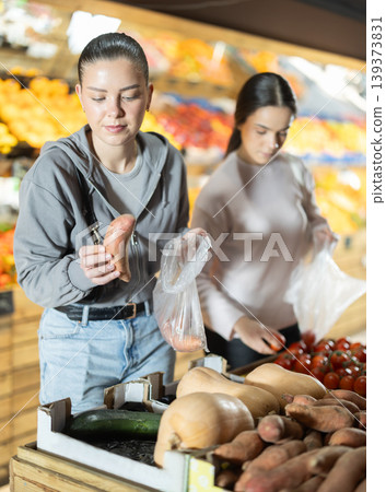Two young women choosing cassava at vegetable store Two young women choosing cassava at vegetable store 139373831