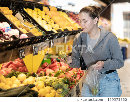 Young woman choosing artichoke in vegetable shop 139373860