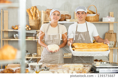 Young woman and man are standing in kitchen with finished bread products Young woman and man are standing in kitchen with finished bread products 139373887