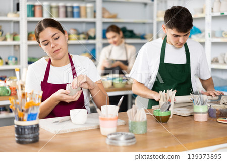 Young woman and young man making pottery Young woman and young man making pottery 139373895