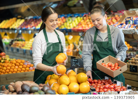 Two sellers place oranges and tomatoes on store counter Two sellers place oranges and tomatoes on store counter 139373905