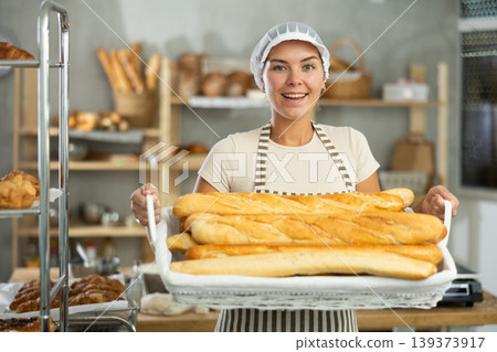 Young woman are standing in kitchen with basket of finished products baguettes Young woman are standing in kitchen with basket of finished products baguettes 139373917