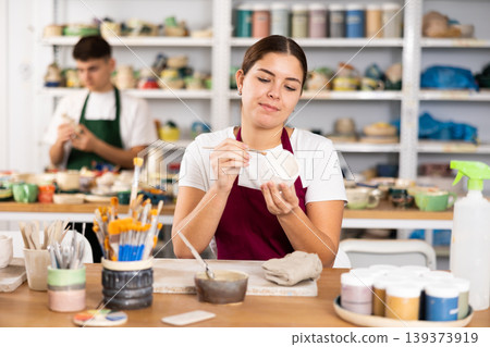 Young woman painting pottery in workshop 139373919
