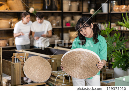 Young Asian female consumer choosing straw jute seats while buying home interior stuff in furniture store Young Asian female consumer choosing straw jute seats while buying home interior stuff in furniture store 139373930