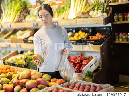 Woman buyer choosing fresh mango at vegetable market Woman buyer choosing fresh mango at vegetable market 139373947