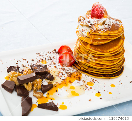 Pancakes served with fruit, honey, chocolate and whipped cream 139374013
