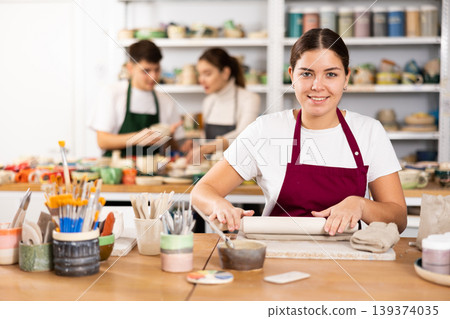 Woman rolling row clay with rolling-pin Woman rolling row clay with rolling-pin 139374035