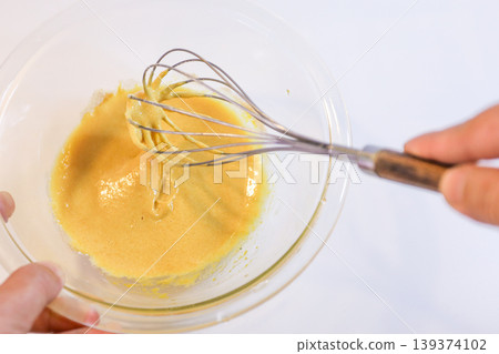 The process of mixing choux pastry dough with a whisk - the steps involved in making sweets. 139374102