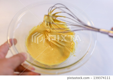 The process of mixing choux pastry dough with a whisk - the steps involved in making sweets. 139374111