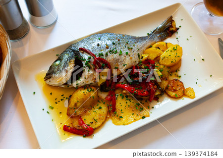 Dorado baked in oven served with bell peppers, green onion and potatoes Dorado baked in oven served with bell peppers, green onion and potatoes 139374184