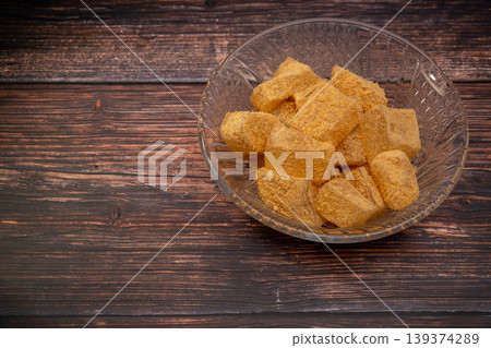 一張照片,照片中一個玻璃容器裡裝著黃豆粉麻糬(裹著烤黃豆粉的年糕),背景是木紋。 一張照片,照片中一個玻璃容器裡裝著黃豆粉麻糬(裹著烤黃豆粉的年糕),背景是木紋。 139374289