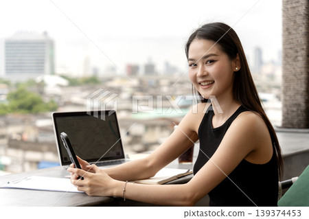 Asian Young Adult Woman Smiling Using Smartphone Laptop Outdoor Cafe City View Blurred Background Digital Nomad Remote Work Lifestyle Technology 139374453