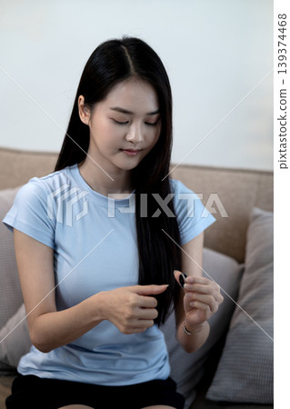Asian woman adult focus small black earbud device preparing using listening music audio podcast wireless technology cozy home living room setting comfort leisure Asian woman adult focus small black earbud device preparing using listening music audio podcast wireless technology cozy home living room setting comfort leisure 139374468