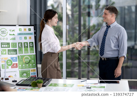 Business professionals handshake discussing ESG green business net zero initiatives promoting sustainability modern office partnership agreement Business professionals handshake discussing ESG green business net zero initiatives promoting sustainability modern office partnership agreement 139374727