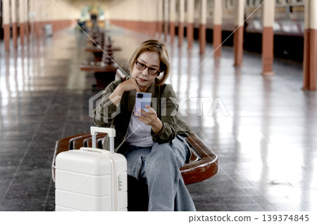 Asian woman traveler adult passenger using smartphone train station platform waiting for departure journey communication Asian woman traveler adult passenger using smartphone train station platform waiting for departure journey communication 139374845