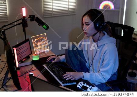 Asian young adult woman live streaming video games home studio setup creating content gaming headset microphone keyboard mouse online broadcast Asian young adult woman live streaming video games home studio setup creating content gaming headset microphone keyboard mouse online broadcast 139374874