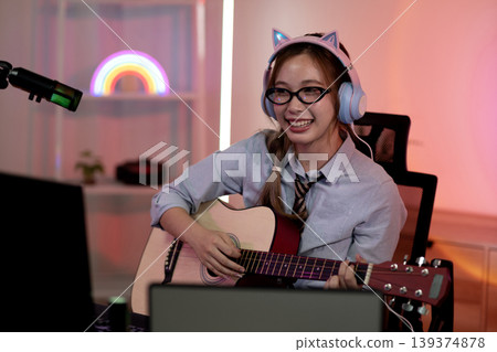 Young Asian woman playing acoustic guitar recording music home studio learning online music education content creation streaming Young Asian woman playing acoustic guitar recording music home studio learning online music education content creation streaming 139374878