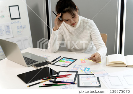 Asian young adult woman designing user interface experience for mobile app development creative professional working office Asian young adult woman designing user interface experience for mobile app development creative professional working office 139375070