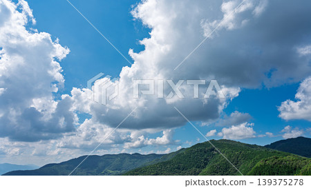 許多白雲飄過湛藍的夏日天空，山巒披上了綠色的外衣。 139375278