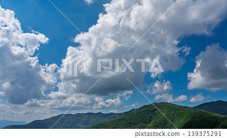 許多白雲飄過湛藍的夏日天空，山巒披上了綠色的外衣。 139375291