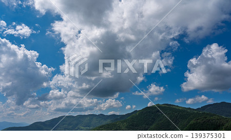 許多白雲飄過湛藍的夏日天空，山巒披上了綠色的外衣。 139375301