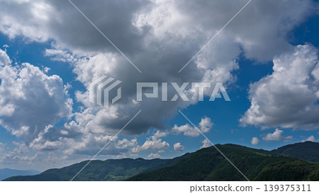 許多白雲飄過湛藍的夏日天空,山巒披上了綠色的外衣。 許多白雲飄過湛藍的夏日天空,山巒披上了綠色的外衣。 139375311