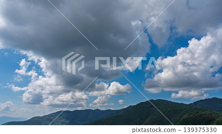 許多白雲飄過湛藍的夏日天空，山巒披上了綠色的外衣。 139375330