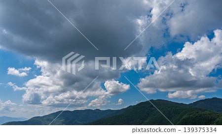 許多白雲飄過湛藍的夏日天空，山巒披上了綠色的外衣。 139375334