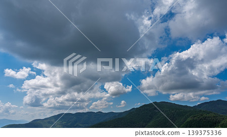 許多白雲飄過湛藍的夏日天空,山巒披上了綠色的外衣。 許多白雲飄過湛藍的夏日天空,山巒披上了綠色的外衣。 139375336
