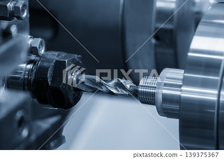 Precision hole making process on a CNC lathe machine using a high-speed drill tool in a blue-toned industrial scene. Precision hole making process on a CNC lathe machine using a high-speed drill tool in a blue-toned industrial scene. 139375367