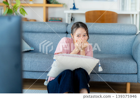 一位年輕的女士在客廳裡看電視 一位年輕的女士在客廳裡看電視 139375946