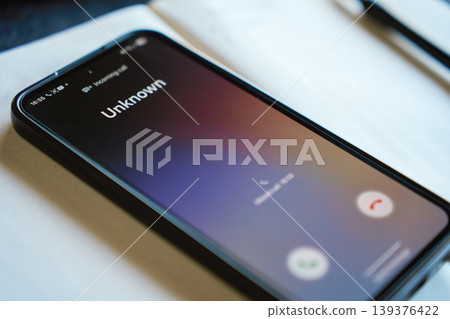 Smartphone screen with unknown incoming call on desk Smartphone screen with unknown incoming call on desk 139376422