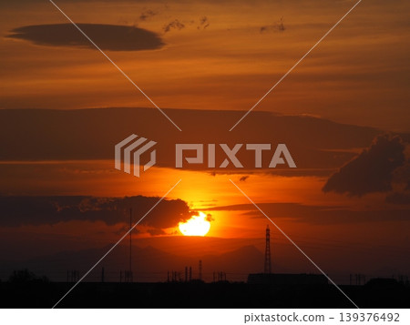 夕陽將天空染成橘色，太陽緩緩沉入城市之下。 139376492
