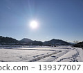 A winter landscape of snow-covered farmland and mountains on a sunny day. 139377007