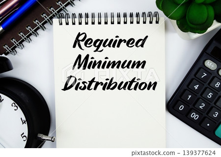 Required Minimum Distribution text written on notepad with calculator and alarm clock 139377624