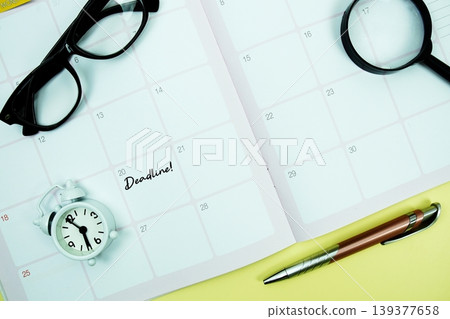 Deadline! message written on calendar date with alarm clock, glasses and magnifying glass on yellow background Deadline! message written on calendar date with alarm clock, glasses and magnifying glass on yellow background 139377658