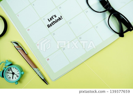 Let's Rethink! message written on calendar date with alarm clock, glasses and magnifying glass on yellow background Let's Rethink! message written on calendar date with alarm clock, glasses and magnifying glass on yellow background 139377659