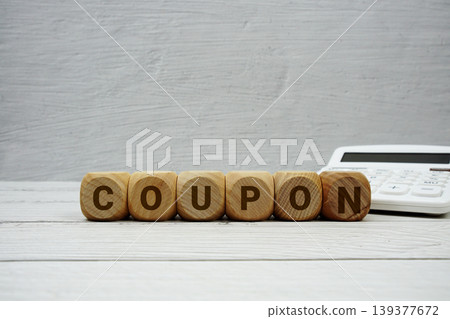 COUPON alphabet letters with calculator on wooden background COUPON alphabet letters with calculator on wooden background 139377672