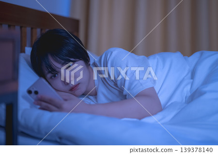 一名婦女在床上的看一個智能手機 139378140