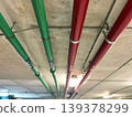 pipes mounted along a concrete ceiling in an industrial facility, perspective lines leading through underground space, infrastructure system details with lighting, modern engineering concept, utility 139378299